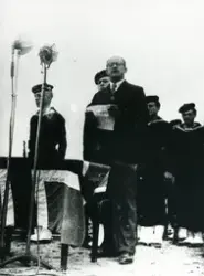Ein av talarane 21.08.1949 då minnesteinen i Telavåg over dei falne under andre verdskrigen vart avduka. Marinegastar i bakgrunnen og mikrofonar er sett opp.