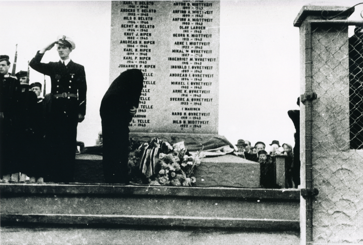 Admiral Briseid legg ned krans 21.08.1949 då minnesteinen i Telavåg over dei falne under andre verdskrigen vart avduka. Deltakarar frå Marinen står like ved i "giv akt". I bakgrunnen kan ein sjå folk som har møtt opp.
