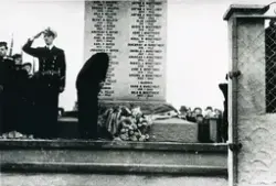 Admiral Briseid legg ned krans 21.08.1949 då minnesteinen i Telavåg over dei falne under andre verdskrigen vart avduka. Deltakarar frå Marinen står like ved i "giv akt". I bakgrunnen kan ein sjå folk som har møtt opp.