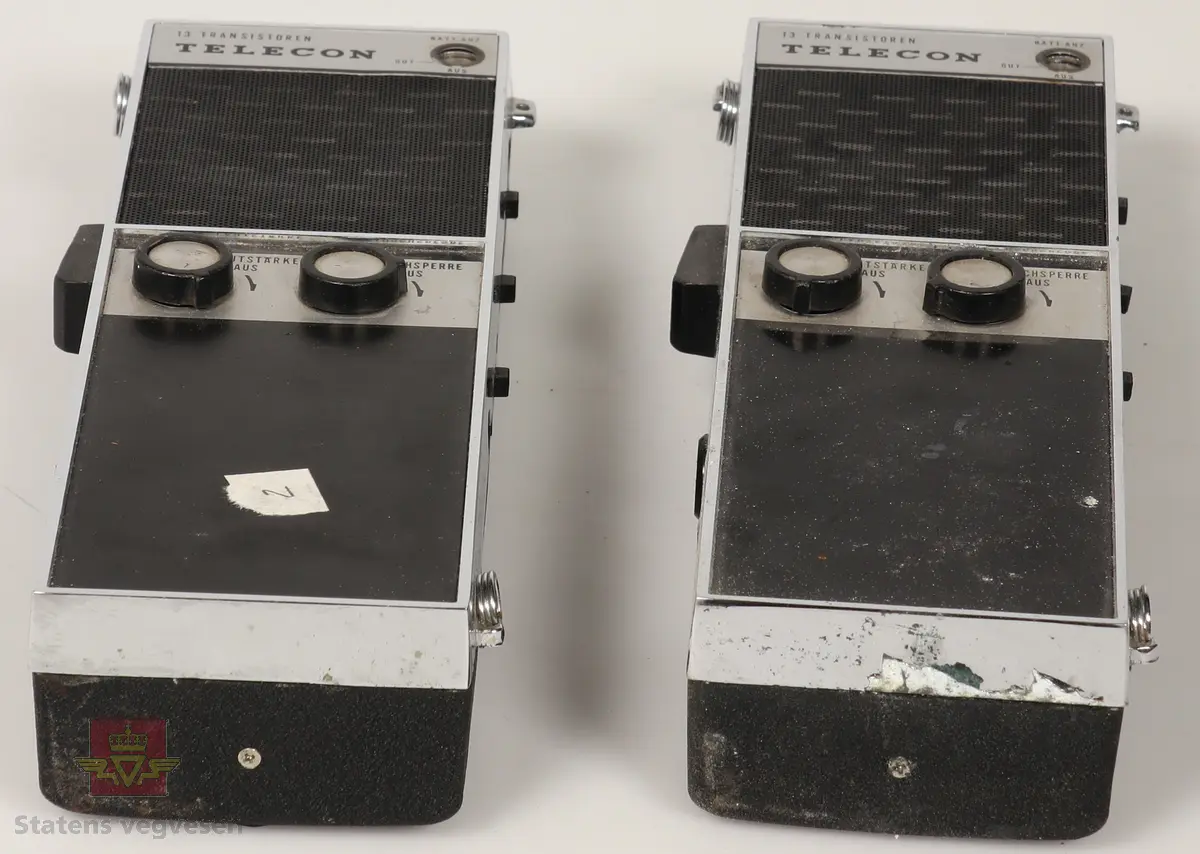 2 stk Walkie Talkie av plast og metall, sølv og svart farget. De er batteridrevet med uttak for 12V drift. Ligger i svarte lærhylstre. Merket med Vegdirektoratet. Lærreim for å bærbarhet. 