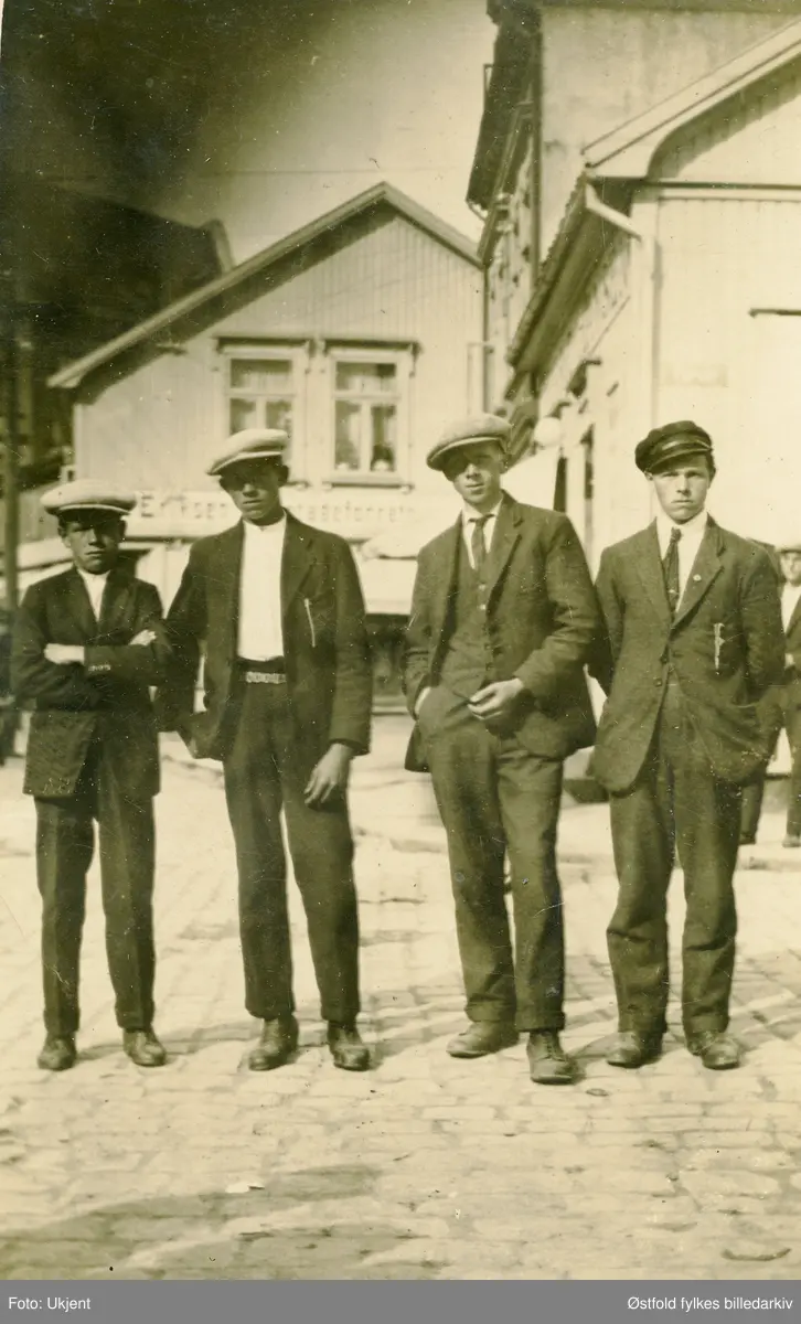 Gruppebilde av unge menn på byen, poserer på Torget i Sarpsborg, ant. 1920-åra, Hans Skogen, Henrik Skogen, Adolf Eriksen (onkel til giver) Anker Pettersen, alle fra Ullerøy.

På bakside av bile er det nortert navn, men nr. 2 og 4 er oppgitt til å være 2. Omar Skogen og 4. Anker xxxxx (vanskelig å tyde)