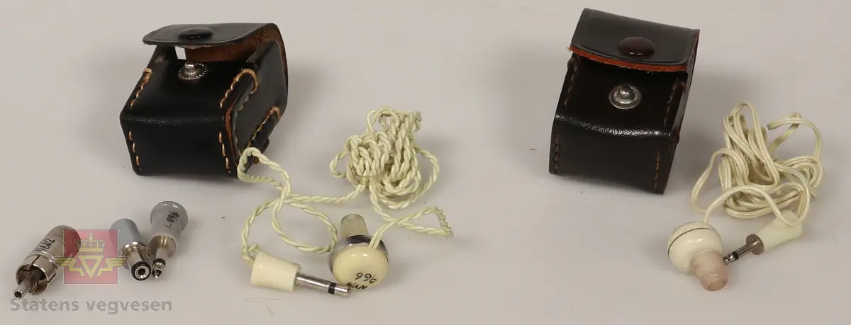 Hørepropper i lær etui. Etuiene er svarte. Høreproppene er hvite. Det hører med ekstra deler i det ene etuiet som er til å plugge inn i forskjellige enheter. Disse er metalliske og med plast på tuppene i grå. 