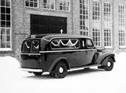 Bårebil eller bregravelsesbil med bilkjennetegn X-8279 parkert utenfor Auto-Karosserifabrikken, Kambo, Moss.