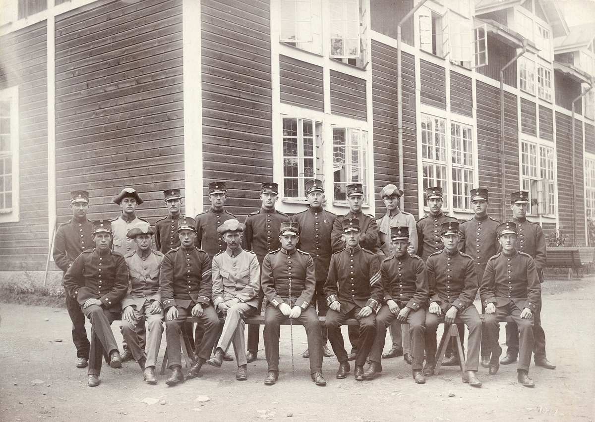 "Harrys pluton, 1912".
En pluton, iklädda två olika typer av uniform (m/95 och m/10), har ställt upp sig för fotografen vid en barack på Kronobergshed, med kompaniofficeren i mitten.
