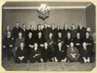 En grupp män i kostym har samlats för gruppfoto, troligtvis i Stockholm. 
Möjligen någon slags fackföreningsmöte (boktryckeri?).