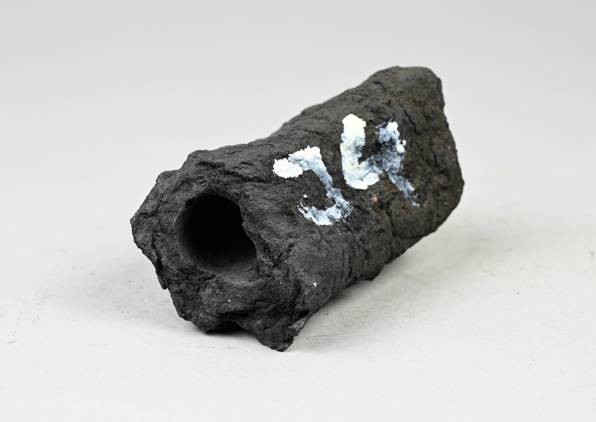 Prov på torvkol. Märkning på provet med vit färg: "J4". Tillhörande lapp med notering: "I4. Torvkol använda i Munkfors. C. G. Särnström. 1889."