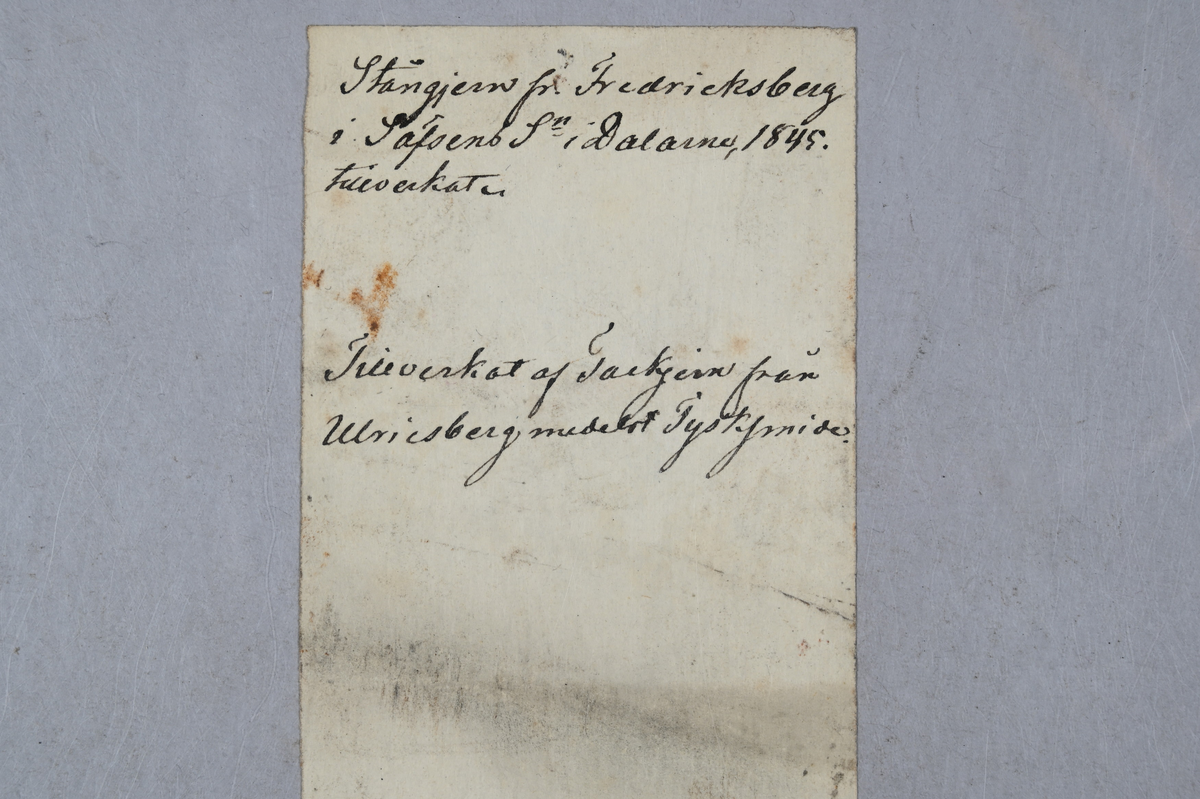 Två prover på stångjärn. Tillhörande lapp med notering: "Stångjern fr. Fredricksberg i Säfsens Sn i Dalarne, 1845 tillverkats. Tillverkat af tackjern från Ulriksberg medelst tysksmide."
