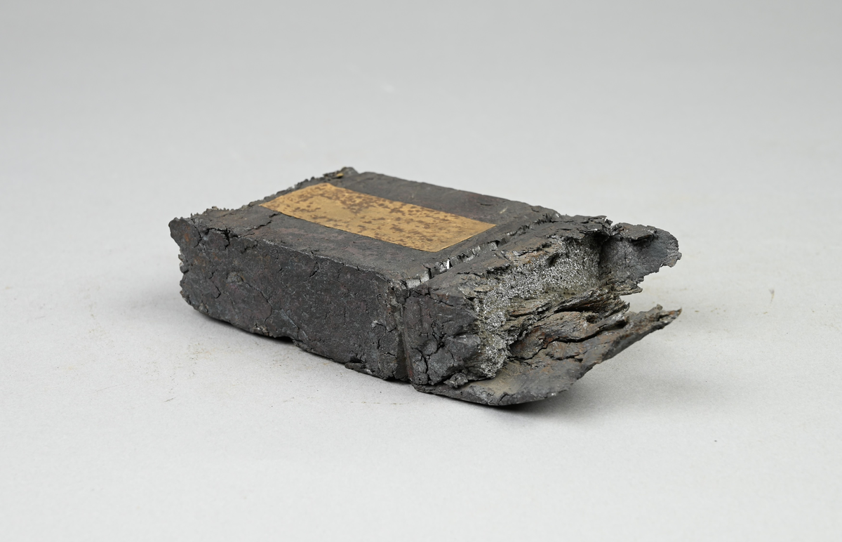 Prov på ovälld puddelsmälta. Påklistrad lapp på provet med notering: "Owälld puddlingssmälta af tackjern. OL (?) ...(?). 82° (?) Puddlingsugnen M...(?) ...(?). Nyby gå..(?) 1838 (?)." Tillhörande lapp med notering: "Ovälld puddelsmälta, utvalsad till råskena."