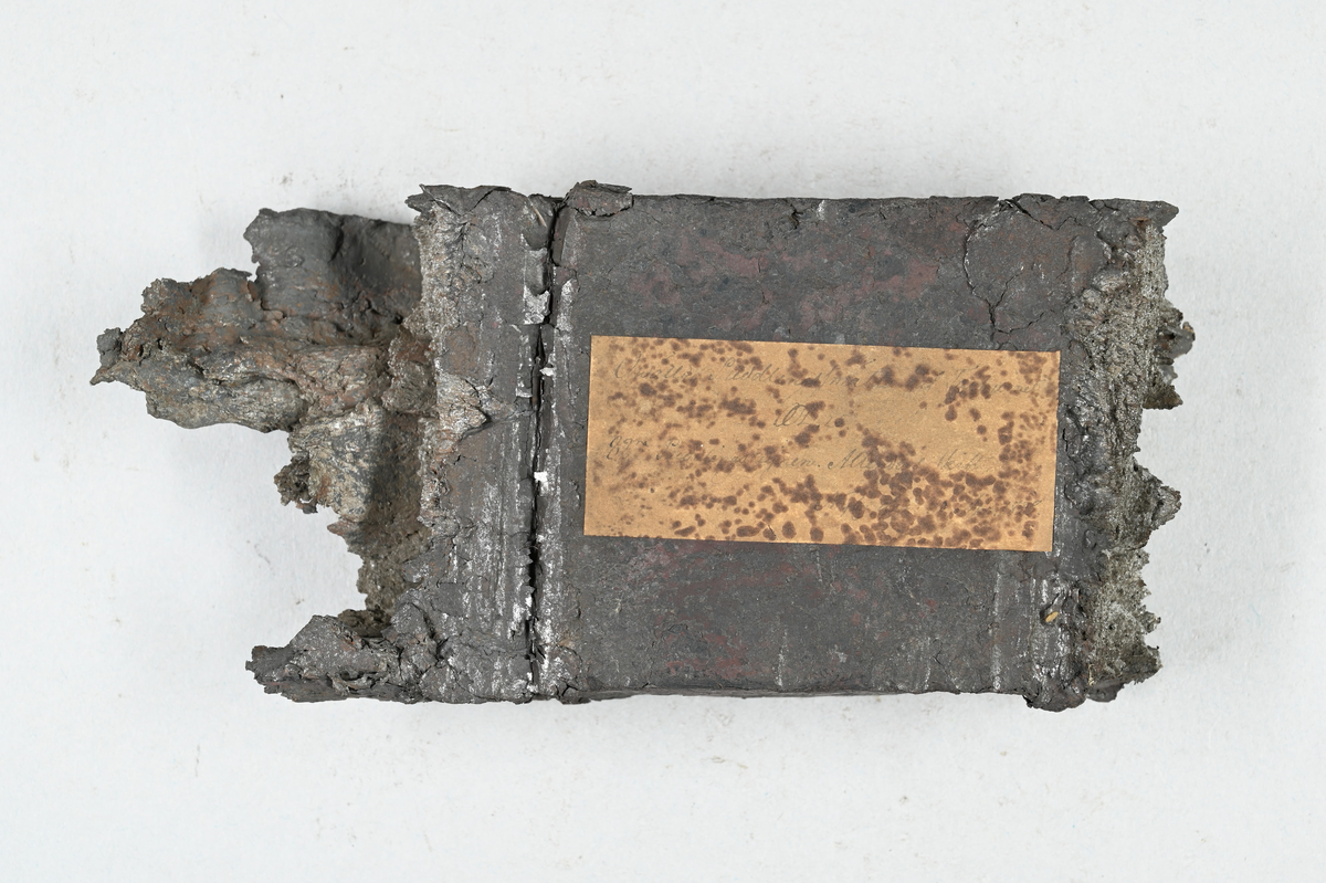 Prov på ovälld puddelsmälta. Påklistrad lapp på provet med notering: "Owälld puddlingssmälta af tackjern. OL (?) ...(?). 82° (?) Puddlingsugnen M...(?) ...(?). Nyby gå..(?) 1838 (?)." Tillhörande lapp med notering: "Ovälld puddelsmälta, utvalsad till råskena."