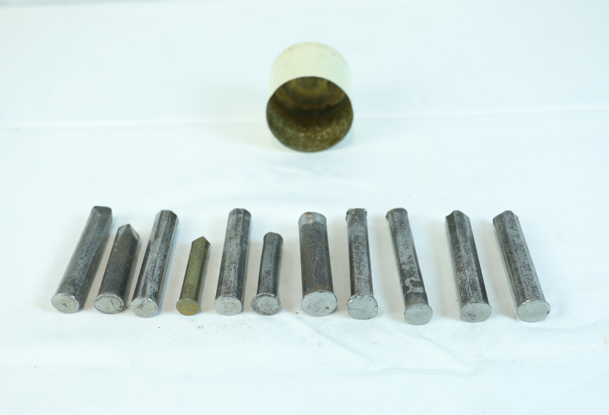 Metallboks uten lokk, med 11 avlange og tykke metallstenger. Trolig brukt til materiale eller verktøy i gullsmedvirksomhet.