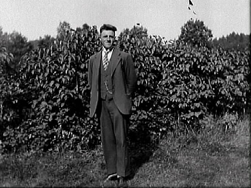 Fotografen själv, John Johansson, står finklädd framför syrenbuskarna. Han bodde hos sina morföräldrar på Tornareds gård i Gällared 1912-1931. Sedan flyttade han tillbaks till föräldrarna i Varberg.