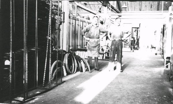 Arbetsplatsinteriör från Monarks cykelfabrik som visar män i produktionen. John Johansson arbetade en tid från sent 1930-tal som cykelarbetare.