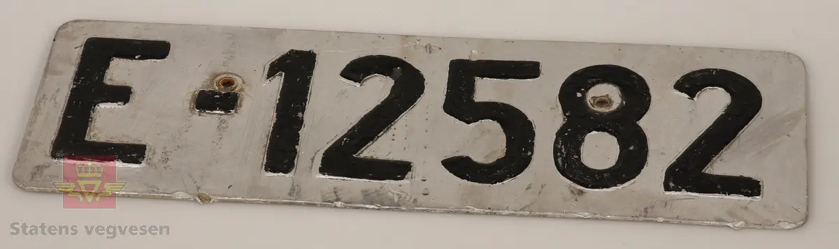 Bilskilt / bil kjennemerker:

- E - 60 8348. Grått skilt. Svart skrift. 
- E - 6477 Hotellvogn. Grått skilt. Svart skrift.
- B - 66958. Grått skilt. Svart skrift. 
- C - 5210. Grått skilt. Svart skrift. 
- C - 727143. Grått skilt. Svart skrift.
- D - 36862. Grønt skilt. Hvit skrift. 
- E - 70167. 2 stk helt likte. Grå. Svart skrift. Buet i form. Trolig sittet på motorsykkel. 
- E - 5050. Grått skilt. Svart skrift. Lagd for drosje. 
- E - 10101. Grått skilt. Svart skrift. 
- D - 1962. Grått skilt. Svart skrift. 
- D - 502139. Grått skilt. Svart skrift.
- E - 6172 Rutevogn. Grått skilt. Svart skrift.
- E - 10722 Leievogn. Grått skilt. Svart skrift. 
- E - 8487. Grått skilt. Svart skrift. 
- X - 69740. 2 stk helt like. Grått skilt. Svart skrift. 
- E - 61144. Framside hvit med rød skrift. Baksiden grønn.
- E - 79195. Grønt skilt. Hvit skrift. 
- E - 11299. Mørk grønt skilt. Hvit skrift. 
- S - 14 674. Grønt skilt. Hvit skrift. 
- F - 38 390. Grått skilt med grønn bakside. Hvit skrift. 
- Z - 56437. 2 stk helt like. Grått skilt. Hvit skrift. 
- E - 70167. Grått skilt. Svart skrift. 
- E - 10237. Grått skilt. Svart skrift. 
- Z - 93772. Grått skilt. Svart skrift.
- X - 62182. Grått skilt. Svart skrift.
- E - 12582. Grått skilt. Svart skrift. 
- E - 57033. Grått skilt. Svart skrift. 
- E - 69728. Grått skilt. Svart skrift. 
- E - 69905. Grått skilt. Svart skrift.
- A - 9444. Grått skilt. Svart skrift. 
- F - 81212. Grått skilt. Svart skrift. 
- C - 2055. Grått skilt. Svart skrift.
- S - 36887. Grått skilt. Svart skrift.
- K - 93482. Grått skilt. Svart skrift.
- I - 4332. Grått skilt. Svart skrift.
- H - 607551. Grått skilt. Svart skrift. 
- T - 49877. Grått skilt. Svart skrift. 
- W - 61974. Grått skilt. Svart skrift. 
- V - 73267. Grått skilt. Svart skrift. 
- U - 92620. Grått skilt. Svart skrift. 
- U - 90282. Grått skilt. Svart skrift. 
- U - 5055. Grått skilt. Svart skrift. 
- T - 90039. Grått skilt. Svart skrift. 
- T - 16746. Grått skilt. Svart skrift. 

