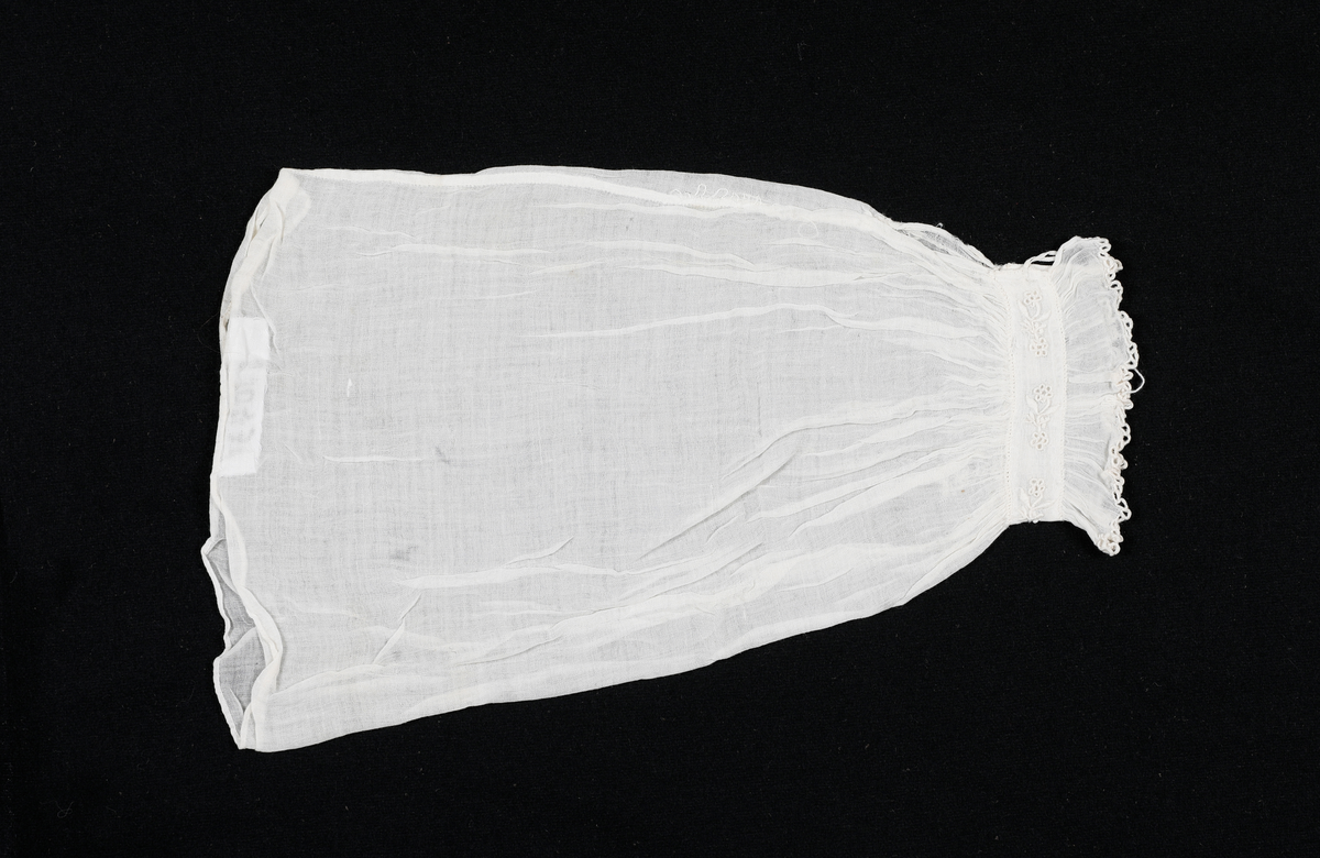 Løserme i tynt stoff. Rynket over og under mansjettlinning. Mansjettlinningen er brodert. Lukkes med hempe og en liten knapp. Sidesømmen i ermet er indresøm. Lappet noen steder. 