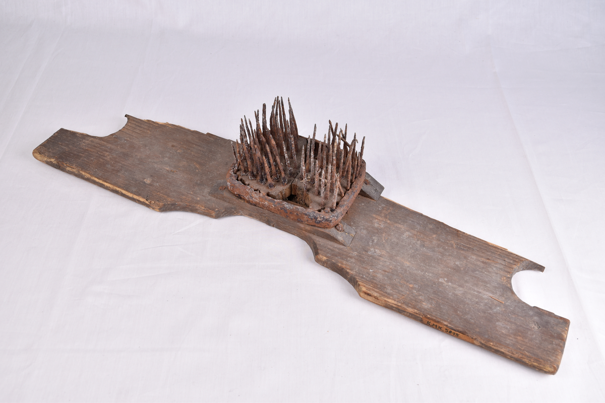 Redskap av tre med pigger (tinder) til å bearbeide lin med.