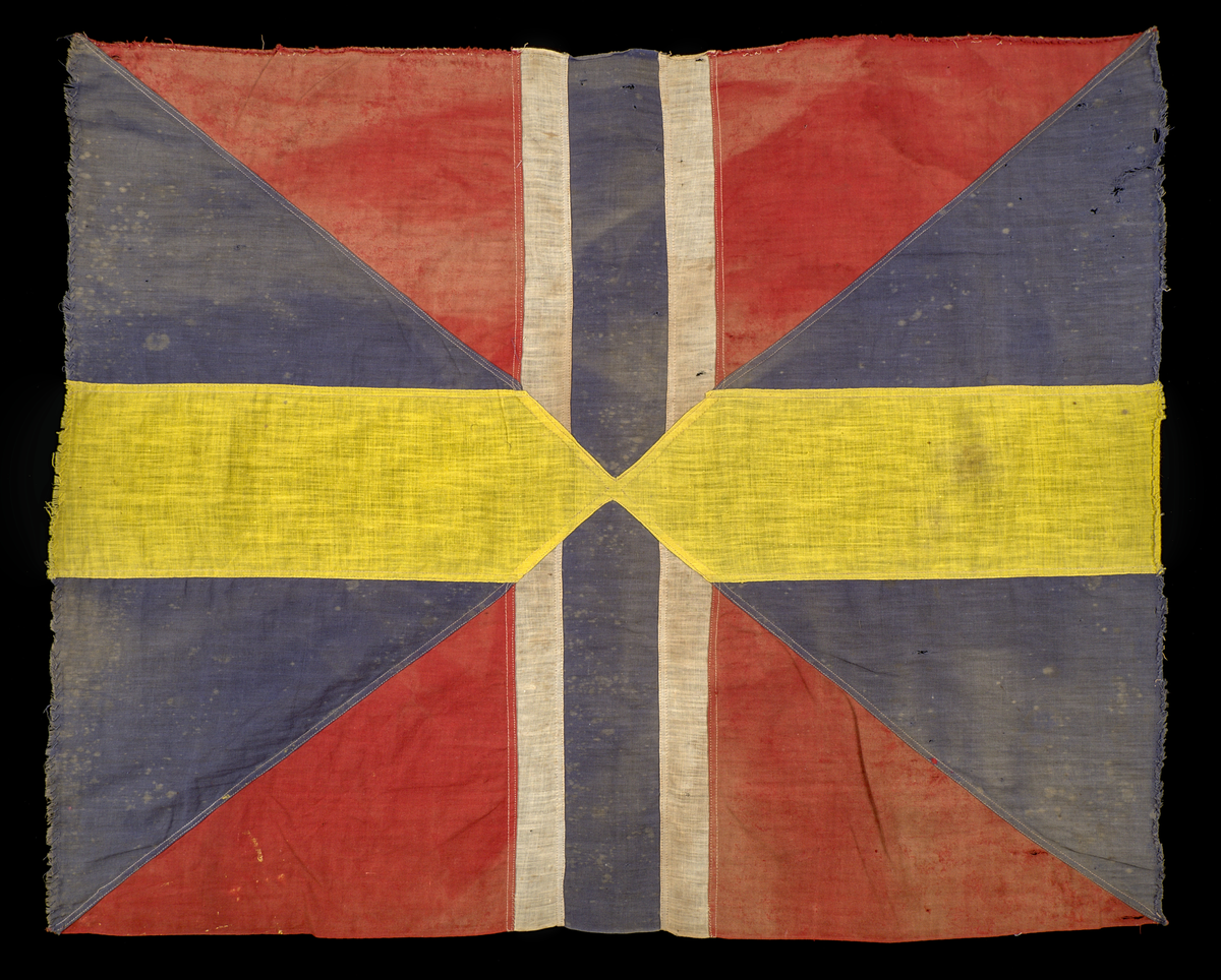 Unionsmärke från svensk-norsk flagga (1844–1905)

Rektangulärt tygmärke, sammansatt av flera tygstycken i tuskaftad bomull, som tillsammans bildar ett korslagt mönster av färgfält i rött, blått, vitt och gult. Styckena är sammanfogade med maskinsydda sömmar i vit bomullstråd.

Föremålet är skört, blekt och delvis nedfläckat med färg. Kaststygnen längs kanterna tillkom i samband med konservering år 2025.
