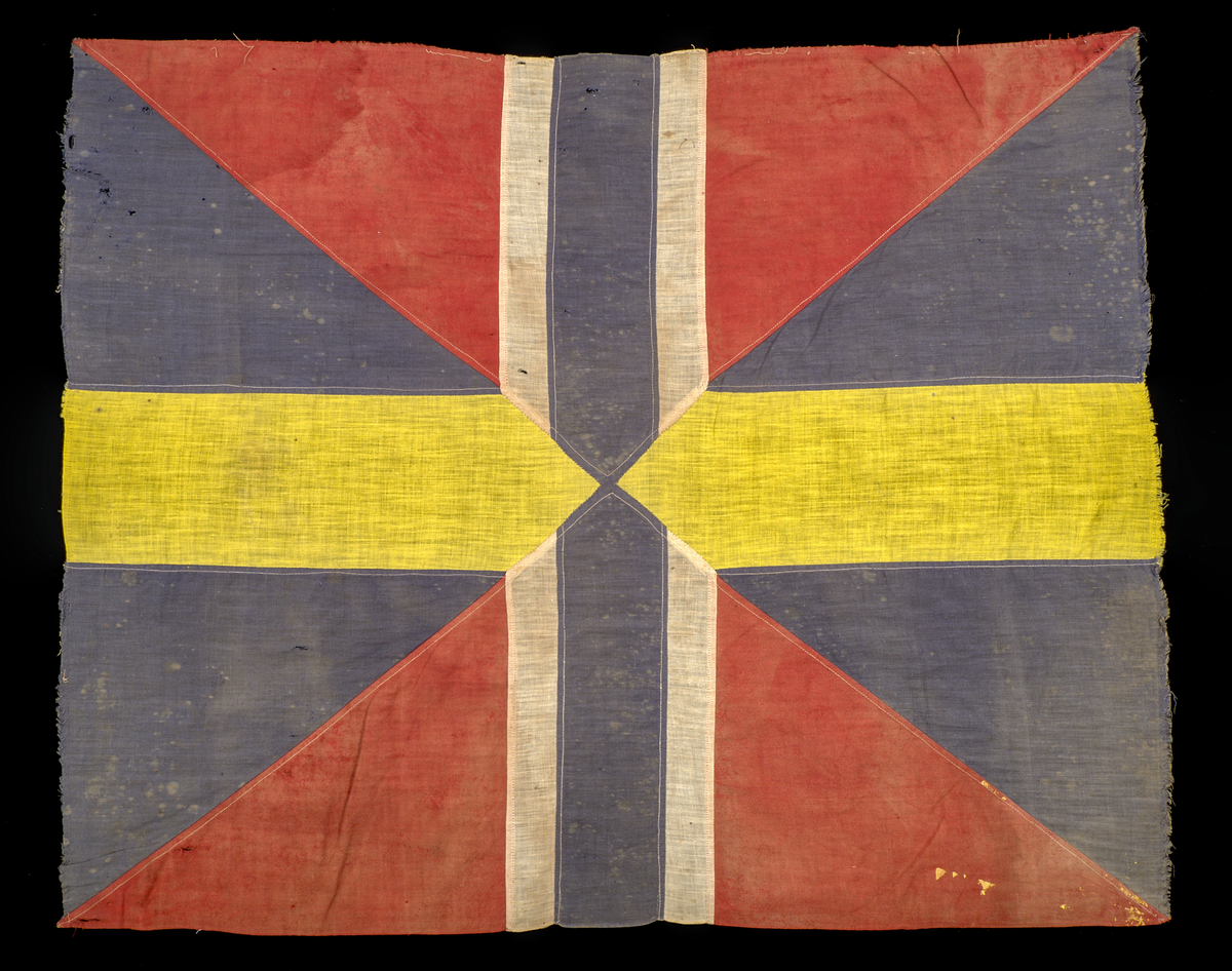 Unionsmärke från svensk-norsk flagga (1844–1905)

Rektangulärt tygmärke, sammansatt av flera tygstycken i tuskaftad bomull, som tillsammans bildar ett korslagt mönster av färgfält i rött, blått, vitt och gult. Styckena är sammanfogade med maskinsydda sömmar i vit bomullstråd.

Föremålet är skört, blekt och delvis nedfläckat med färg. Kaststygnen längs kanterna tillkom i samband med konservering år 2025.
