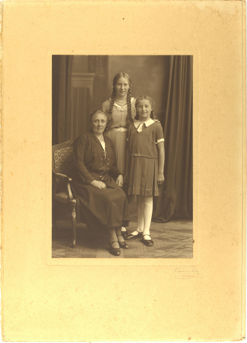 Atelierportrett, en eldre kvinne og to jenter. Gjevar har opplyst at dei heiter Jakobina, Dorret, Gyda - etternamn ukjent (kan vere Øglænd-familien).