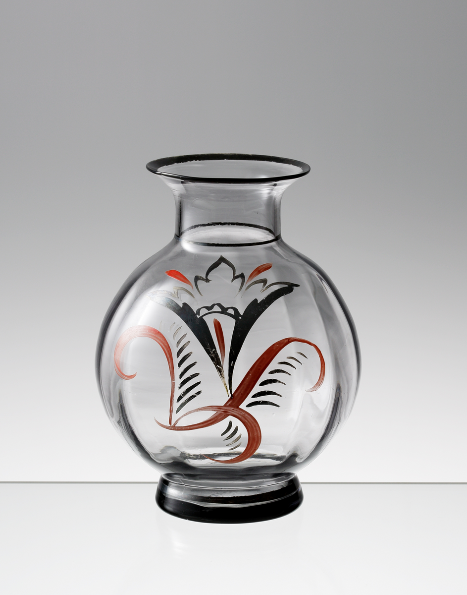 Rökfärgad räfflad vas. Rund buk och utvikt mynnning. Målat stiliserat motiv i rött och svart, samt svartmålad mynningskant.