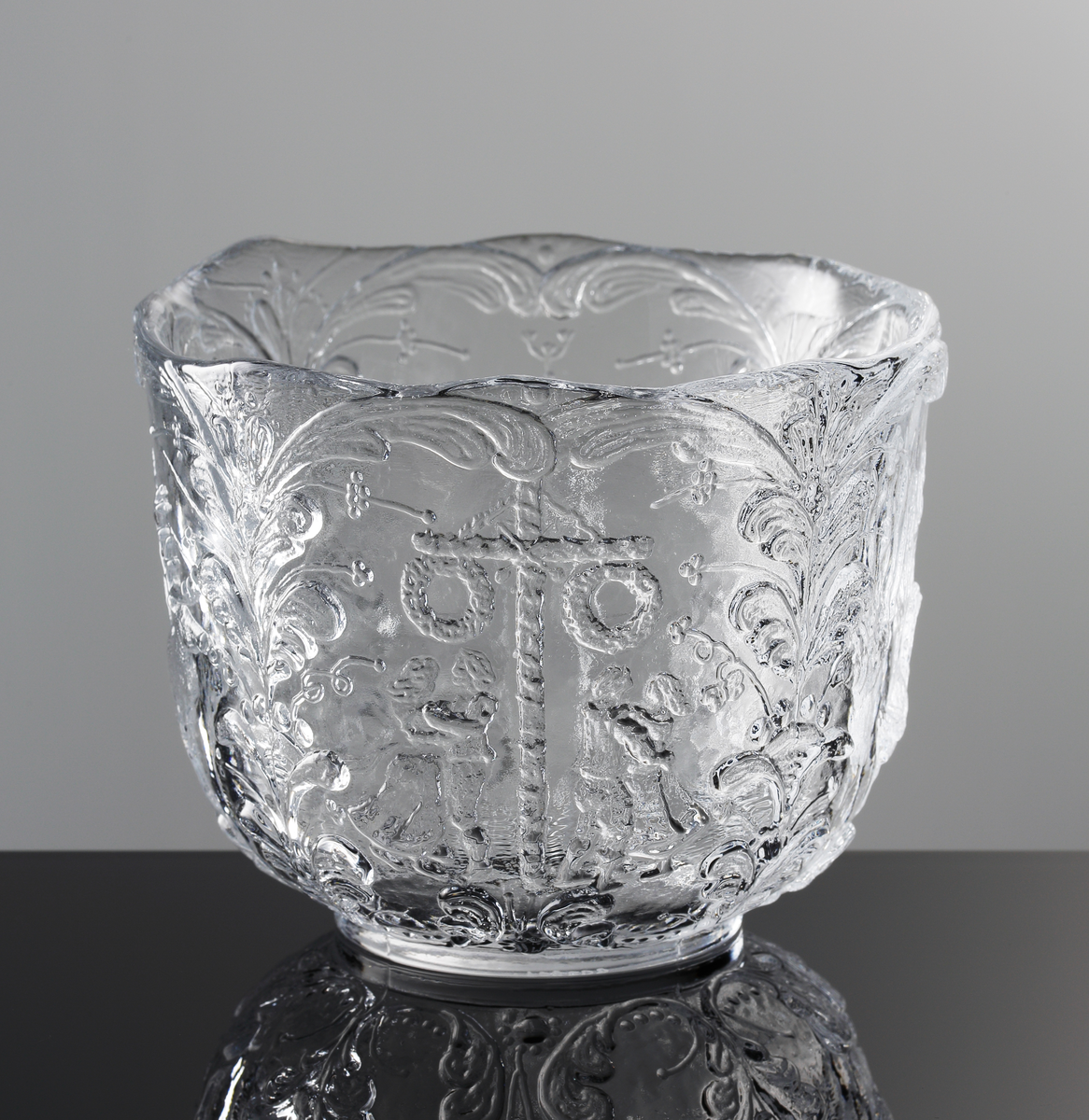 Formgiven av Kjell Engman. Reliefmönster i form av fyra olika typiska svenska motiv mellan stående kurbitsmönster: Nils Holgersson, statshuset, en kåta och en ren, midsommarstång med dans.