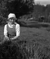 Kvinna sittandes på gräsmatta.