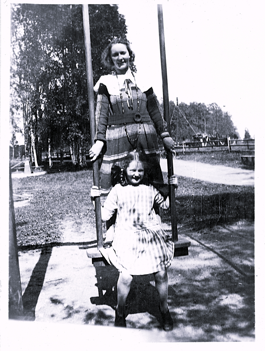 Foto av Margit (Kassan) och Inga som leker i Jädraåparken, Sandviken (enligt text vid bild i album). Text baksida kort: "Kassan och Inga".