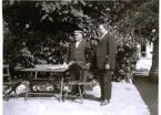 Foto av farbror John och Olle i Vaxholms park och badhotellet (enligt text vid bild i album). Text baksida kort: I Vaxholm 1924.