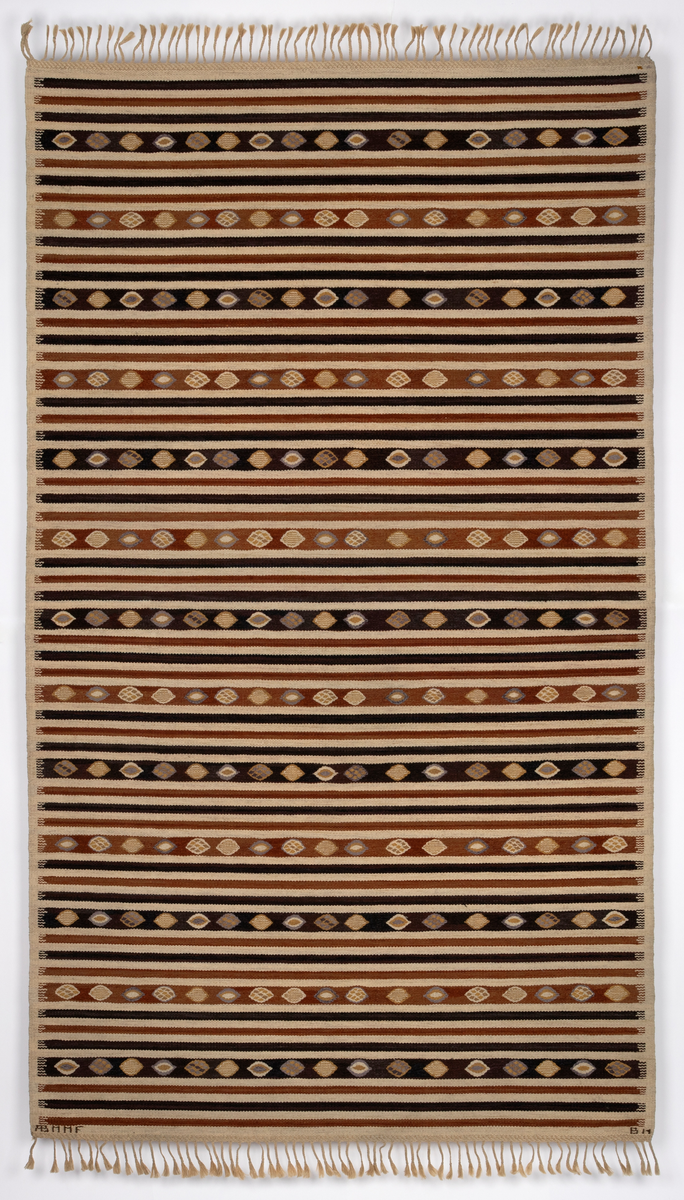 Gulvteppet vevd i röllakanteknikk. Lingarn i renningen og nauthårsgarn i innslaget. Stripet i hvitt, rødbrunt og brunsvart i innlagsretningen, sju smale striper veksler med en bredere stripe hver 25. cm. I de brede stripene er det vevd inn spissovale former med hvitt, lilla og gult fylldekor bestående av avvekslende flekker, striper og spissovaler. På langsidene en 3 cm bred jarekant i hvitt. I teppets kortender er det knyttet frynser av renningen.