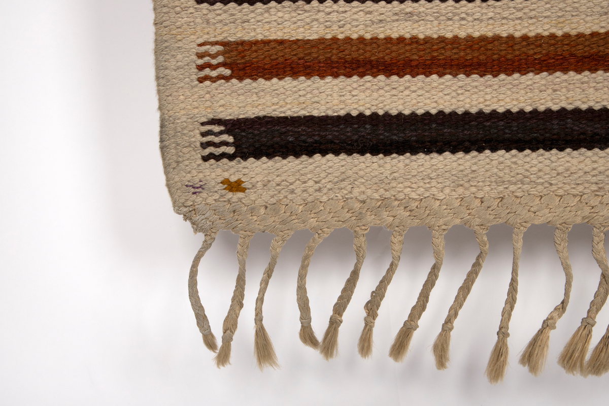 Gulvteppet vevd i röllakanteknikk. Lingarn i renningen og nauthårsgarn i innslaget. Stripet i hvitt, rødbrunt og brunsvart i innlagsretningen, sju smale striper veksler med en bredere stripe hver 25. cm. I de brede stripene er det vevd inn spissovale former med hvitt, lilla og gult fylldekor bestående av avvekslende flekker, striper og spissovaler. På langsidene en 3 cm bred jarekant i hvitt. I teppets kortender er det knyttet frynser av renningen.