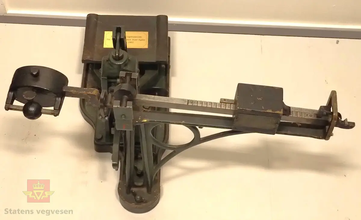 Grønn vekt av metall. I bra stand. En påsatt gullfarget messingplate hvor det står at dette er en gave fra SVV Aust - Agder. 
Tilbehør består av:
NVM 01508 - 001 Påkjøringsrampe av tre, grønnmalt. Har metallbeslag. Brukt for å kjøre av og på bilvekt.
NVM 01508 - 002 Påkjøringsrampe av tre, grønnmalt. Har metallbeslag. Brukt for å kjøre av og på bilvekt.
NVM 01508 - 003 Svart lodd av jern, til bilvekt. Innstøpt i loddet 500 KG. 