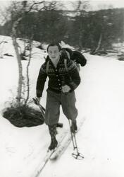Ung mann på ski med ryggsekk gjennom vinterlandskap