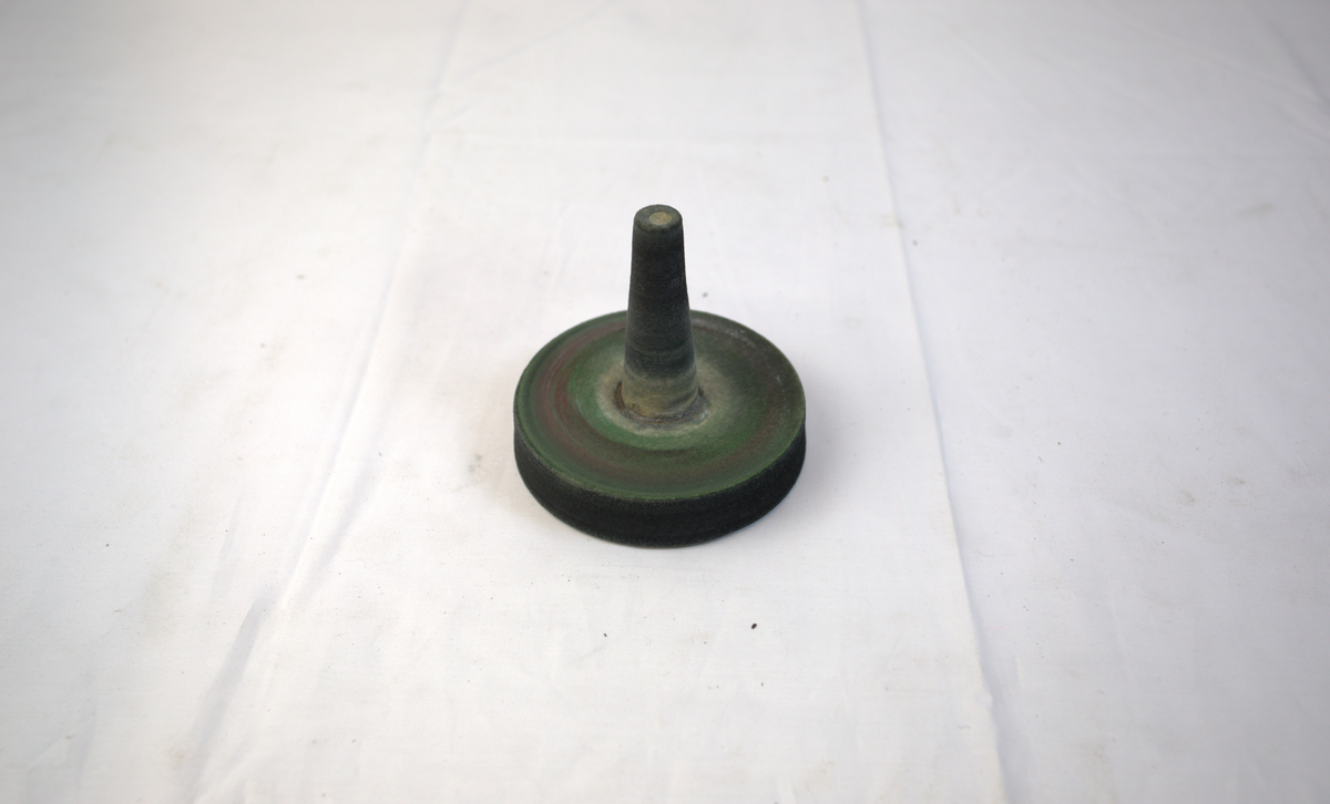 Sirkelformet polerstikkel med utstikkende del. Brukt som poleringsverktøy i gullsmedvirksomhet.