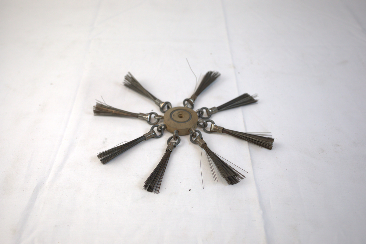 Polerstikkel brukt i gullsmedvirksomhet. I midten er det en sirkelformet gjenstand i tre. I denne er det festet åtte stålbørster.