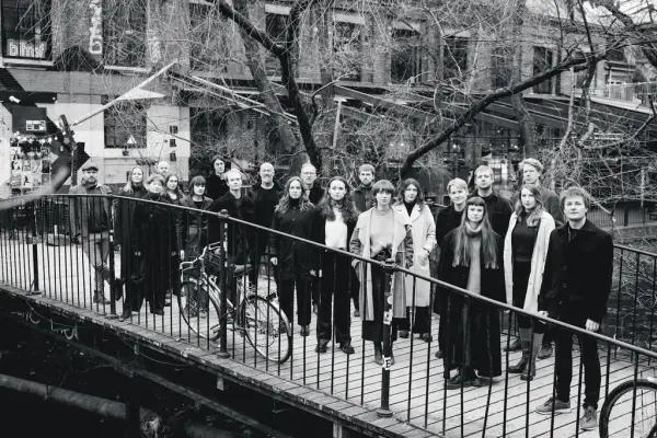 svart kvitt bilde av Oslo kammerkor som står på ei trebru