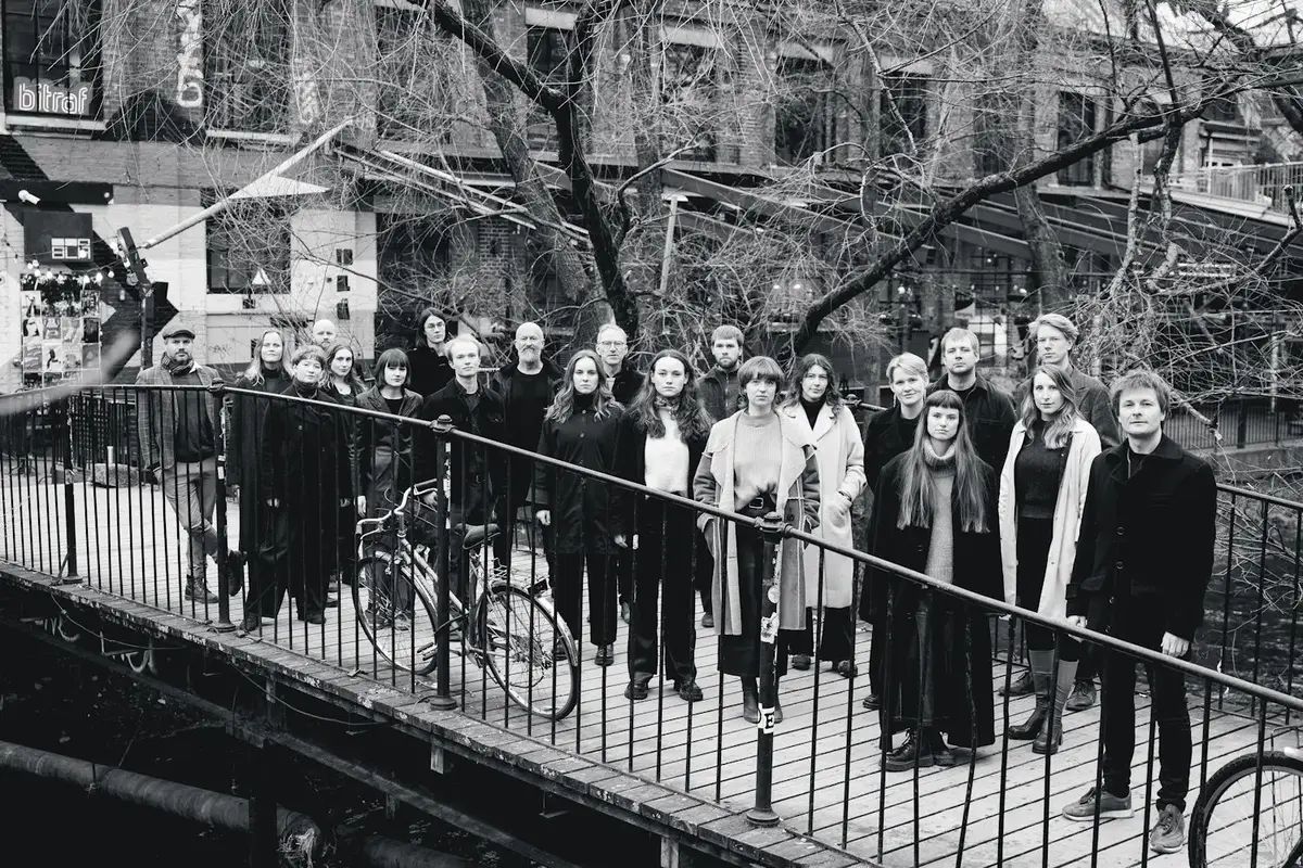 svart kvitt bilde av Oslo kammerkor som står på ei trebru