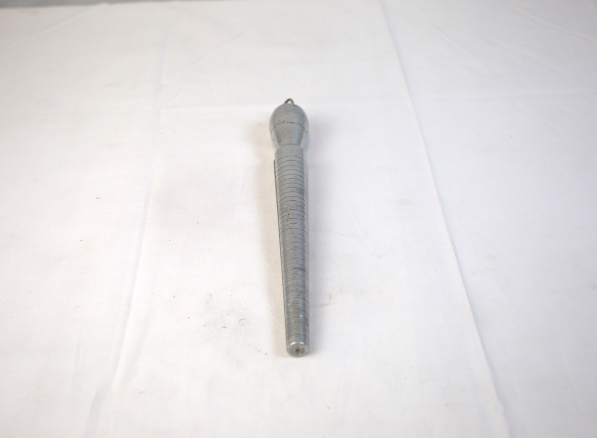 Verktøy til bruk for å lage ringer. Den har striper som går rundt den tilspissede delen. På den ene siden er det også tall i stigende rekkefølge. 