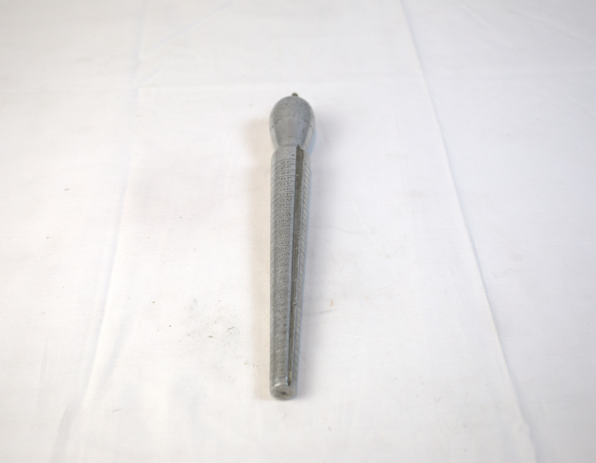 Verktøy til bruk for å lage ringer. Den har striper som går rundt den tilspissede delen. På den ene siden er det også tall i stigende rekkefølge. 