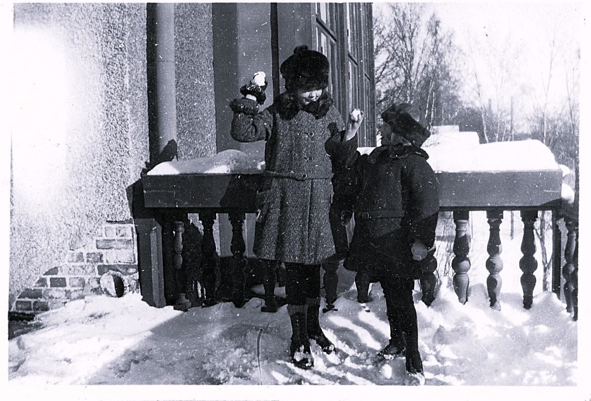 Foto av två barn som är vinterklädda och håller i varsin snöboll. Text baksida kort: "Slarva ej bort korten utan göm dom med hem igen, köp ett album och sätt dom i, de kostar 30 öre st".
