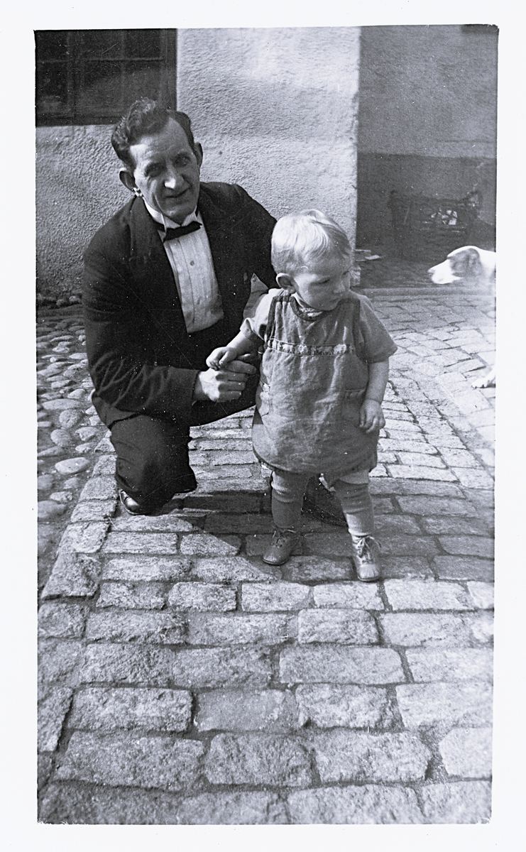 Foto av Björkdalh med sonen Rune (enligt bildtext i album). 
Text baksida kort: "den 2 maj 1926. Rune och pappa på Kontinentals bakgård".