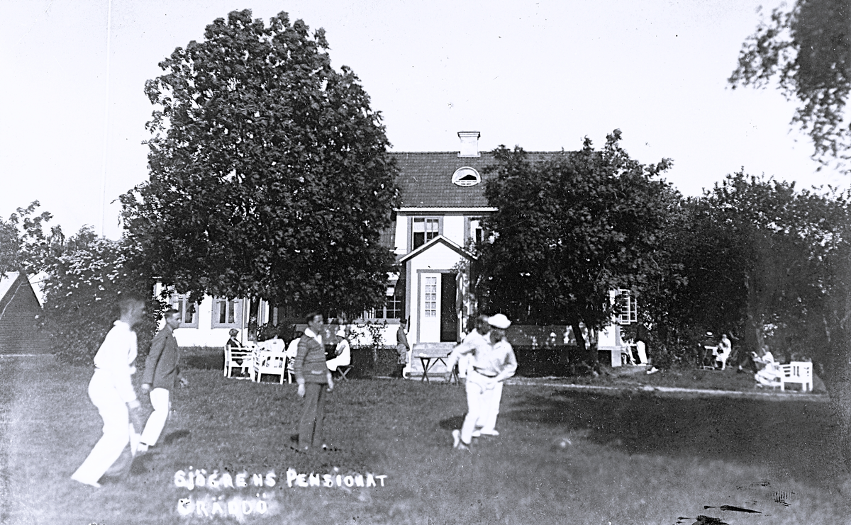 Foto av Sjögrens Pensionat, Gräddö, med fotbollsspelande män i full fart. Text baksida kort: "Gräddö 21-7-1926. Många hälsningar från tant Signe. Adresserat till: Inga och Olle Svensson, Brukshotellet, Sandviken".