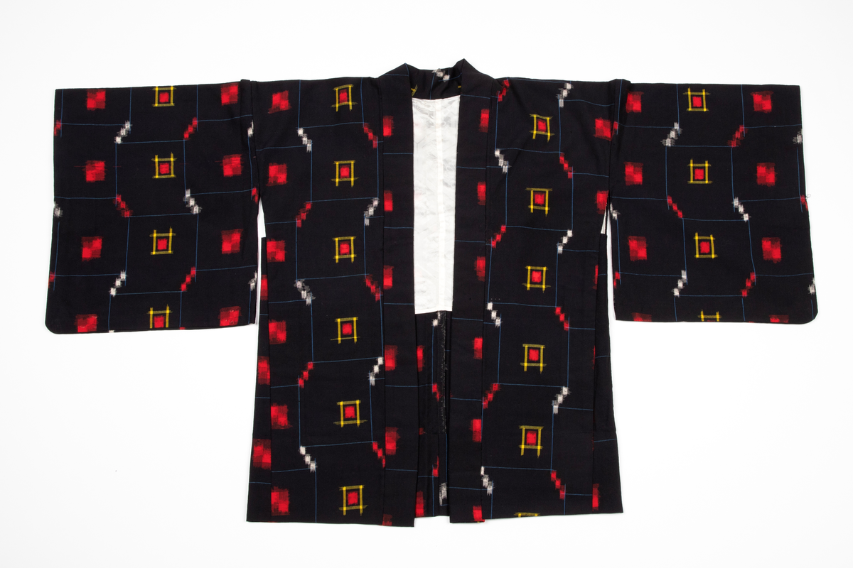 Antrekk som består av en ikatvevd kimono med jakke (haori) i mørkeblå, tynn ull med geometrisk mønster i blått, rødt, hvitt og gult og en underkimono (nagajuban) i rosa og hvit silkekrepp med mønster av traner og bølger. Øvre del av jakken er fôret med hvit, mønstret silkestoff. Tilbehøret består av to knyttebånd i rosa, vevd silke (Ginde-bånd), et reserve-kragestykke (hanori) i silkekrepp til underkimonoen og en elastisk strikk med metallklips til dandering diagonalt over brystet for at plaggene skal sitte pent under. Det følger med et par sokker (tabi) i hvit silke med metallspenner og bomullsfôr og et par sko av geta-typen i svart plast og rødt og hvitt kunstskinn med skinnsåler. To stoffstykker i samme stoff som kimonoen og underkimonoen, antagelig til reparasjon av plaggene.