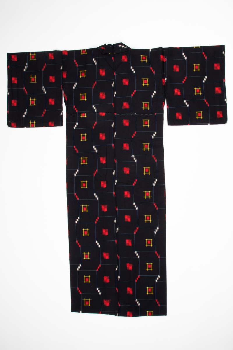Antrekk som består av en ikatvevd kimono med jakke (haori) i mørkeblå, tynn ull med geometrisk mønster i blått, rødt, hvitt og gult og en underkimono (nagajuban) i rosa og hvit silkekrepp med mønster av traner og bølger. Øvre del av jakken er fôret med hvit, mønstret silkestoff. Tilbehøret består av to knyttebånd i rosa, vevd silke (Ginde-bånd), et reserve-kragestykke (hanori) i silkekrepp til underkimonoen og en elastisk strikk med metallklips til dandering diagonalt over brystet for at plaggene skal sitte pent under. Det følger med et par sokker (tabi) i hvit silke med metallspenner og bomullsfôr og et par sko av geta-typen i svart plast og rødt og hvitt kunstskinn med skinnsåler. To stoffstykker i samme stoff som kimonoen og underkimonoen, antagelig til reparasjon av plaggene.