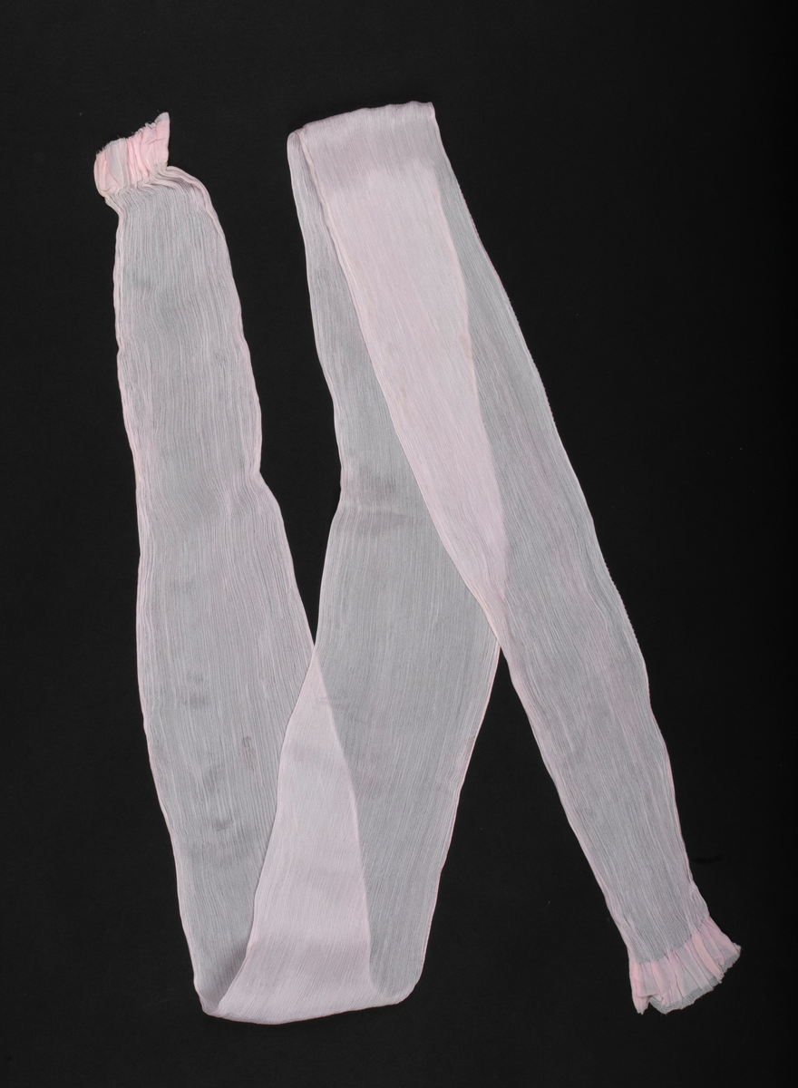 Antrekk som består av en ikatvevd kimono med jakke (haori) i mørkeblå, tynn ull med geometrisk mønster i blått, rødt, hvitt og gult og en underkimono (nagajuban) i rosa og hvit silkekrepp med mønster av traner og bølger. Øvre del av jakken er fôret med hvit, mønstret silkestoff. Tilbehøret består av to knyttebånd i rosa, vevd silke (Ginde-bånd), et reserve-kragestykke (hanori) i silkekrepp til underkimonoen og en elastisk strikk med metallklips til dandering diagonalt over brystet for at plaggene skal sitte pent under. Det følger med et par sokker (tabi) i hvit silke med metallspenner og bomullsfôr og et par sko av geta-typen i svart plast og rødt og hvitt kunstskinn med skinnsåler. To stoffstykker i samme stoff som kimonoen og underkimonoen, antagelig til reparasjon av plaggene.