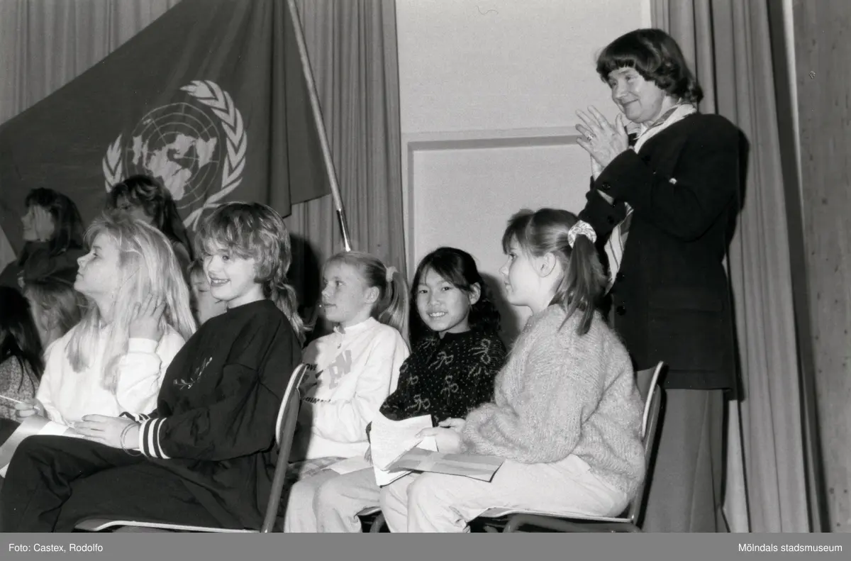 Ordföranden i svenska Unicef-kommittén Lisbeth Palme vid en sammankomst för Unicef i Fässbergsgymnasiets aula i Mölndal, slutet av 1980-talet eller början av 1990-talet. Framför Lisbeth sitter några barn.