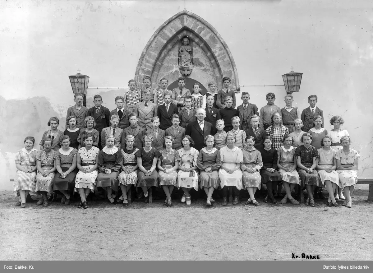 Konfirmanter 1937 utenfor Eidsberg kirke med presten Gunnar Dehli. Dehli var sogneprest i Eidsberg fra 1935 til 1951. Alle konfirmanter er ukjente.