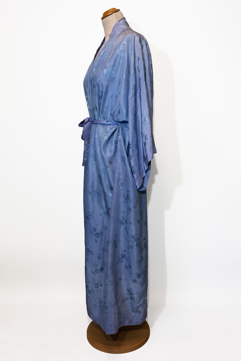 Morgonrock, hellång med tillhörande skärp i ljusblå siden med blommönster i samma färg.