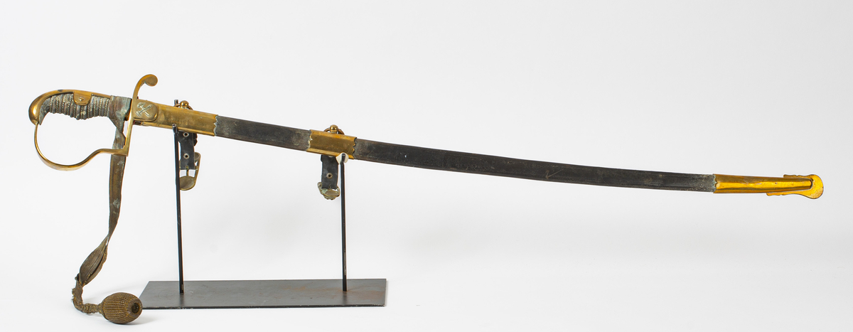 Sabel med svakt buet klinge som er dekorert med ornamenter. Grepet er i sølvfarget metall formet som riller med flettemønster og på oversiden er det messingbeslag som er festet til en buet parerbøyle, også i messing.  Parerstang med bergmannssymbolet (hammer og bergsjern). Balg av sort skinn med messingbeslag og ringer hvor det er festet skinnremmer med spenner for å feste sabelen til et belte. Spennene er støpt med løvehodemotiv. Rundt håndtaket er det tredd et bånd av metalltråd som har en kule i enden.