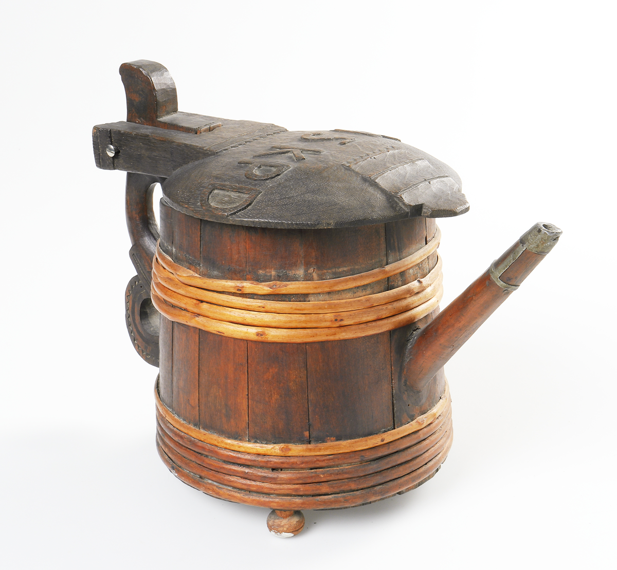 Strutkanna av trä. Laggad kanna med pip. I pipens infattning av tenn. Lock och handtag utsmyckade med tandornamentik. På locket står bosktäverna I N S K P D i relief. Kannan står på tre kulfötter - den ena till hälften av. I botten en lapp skriven av G.O. "Struta-kanna från Lädja Bergs socken Wärend 1865."

Inskrivet i huvudbok 1867.