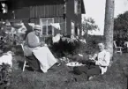 Dam och man sitter i en trädgård och fikar, tidigt 1900-tal.