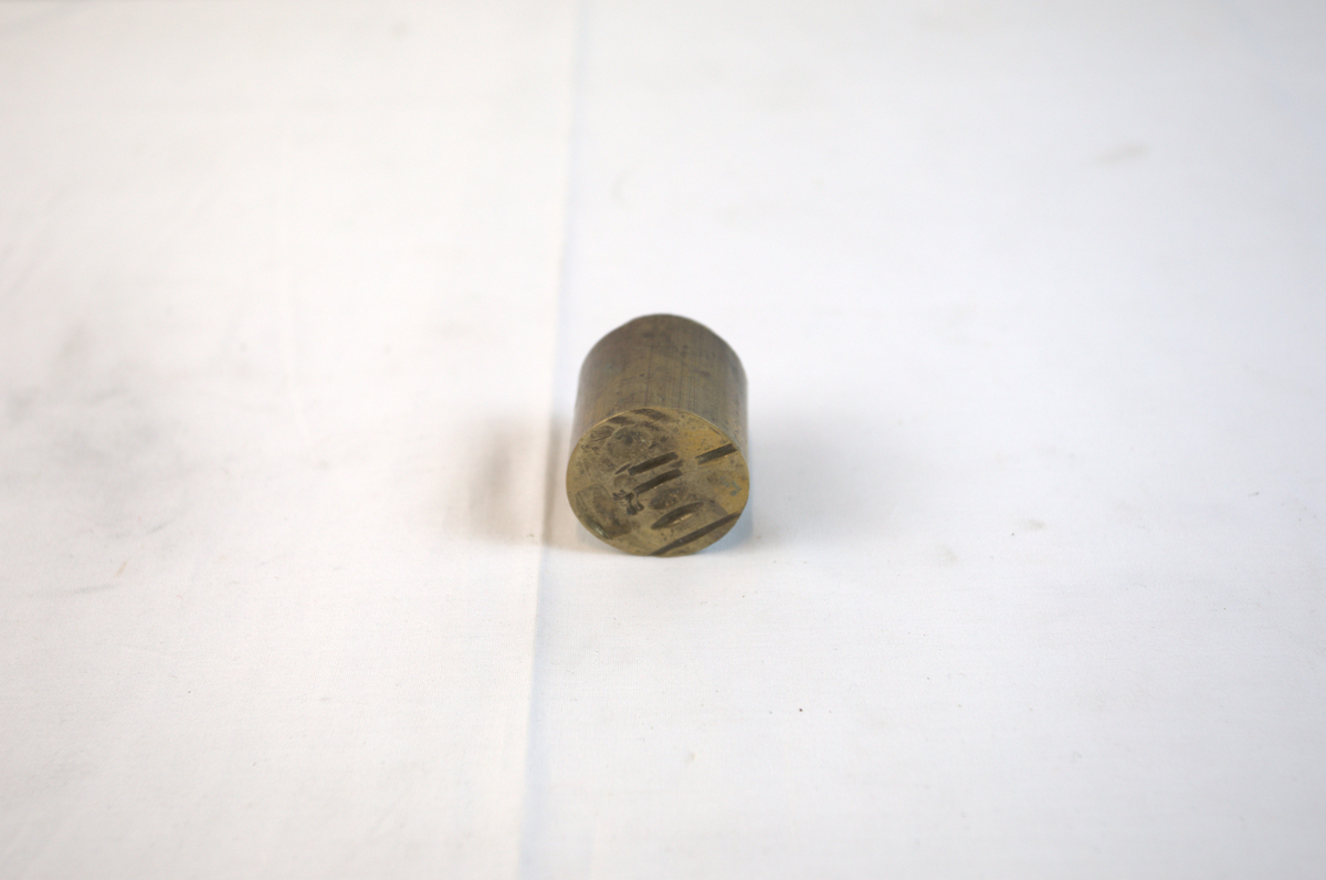 Sirkelformet metallgjenstand med fordypning i toppen. 